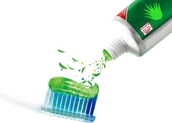 A toothpaste tube with aloe vera extract being applied to a toothbrush, emphasizing oral health benefits.